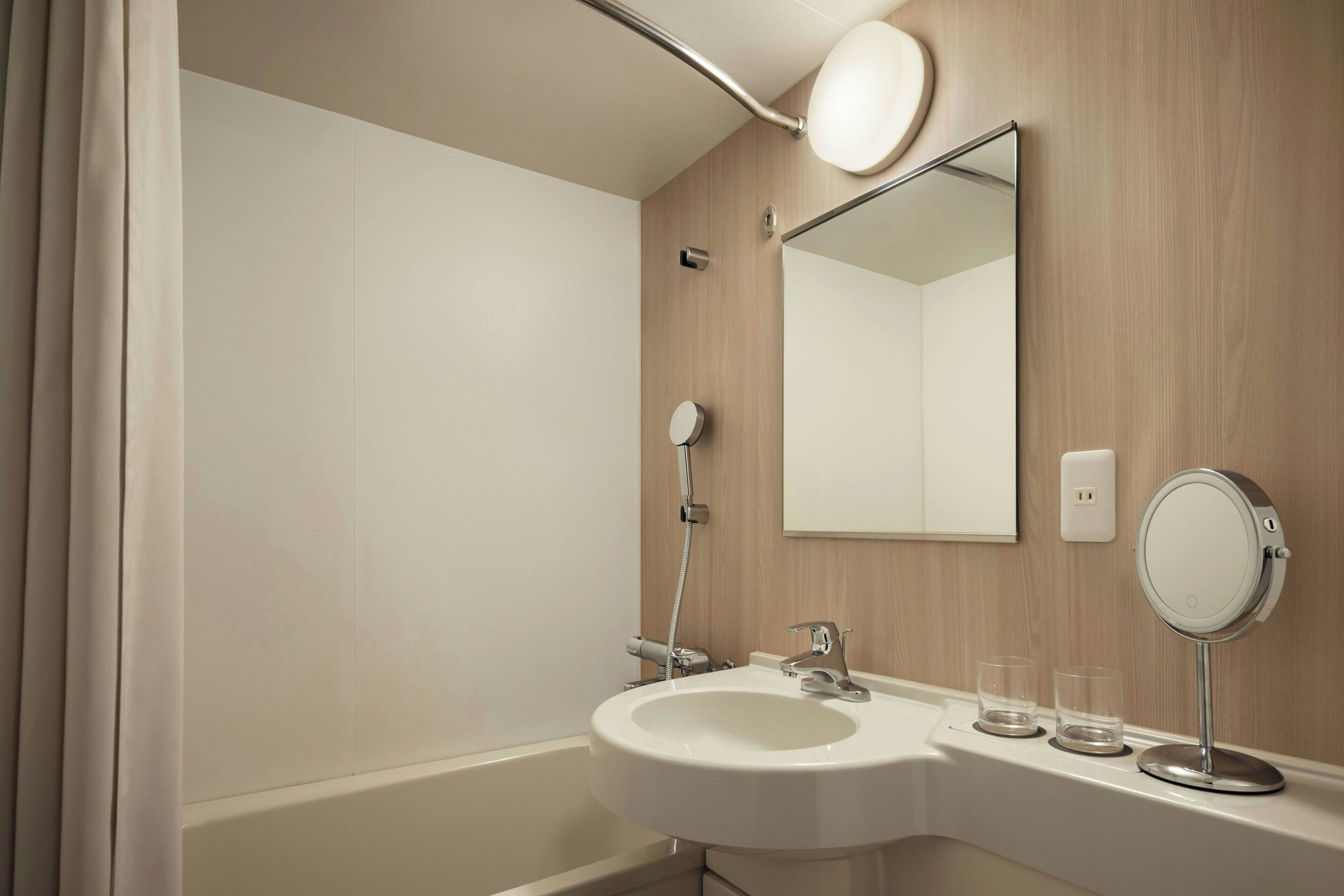 A bathroom with a sink, mirror, and shower.