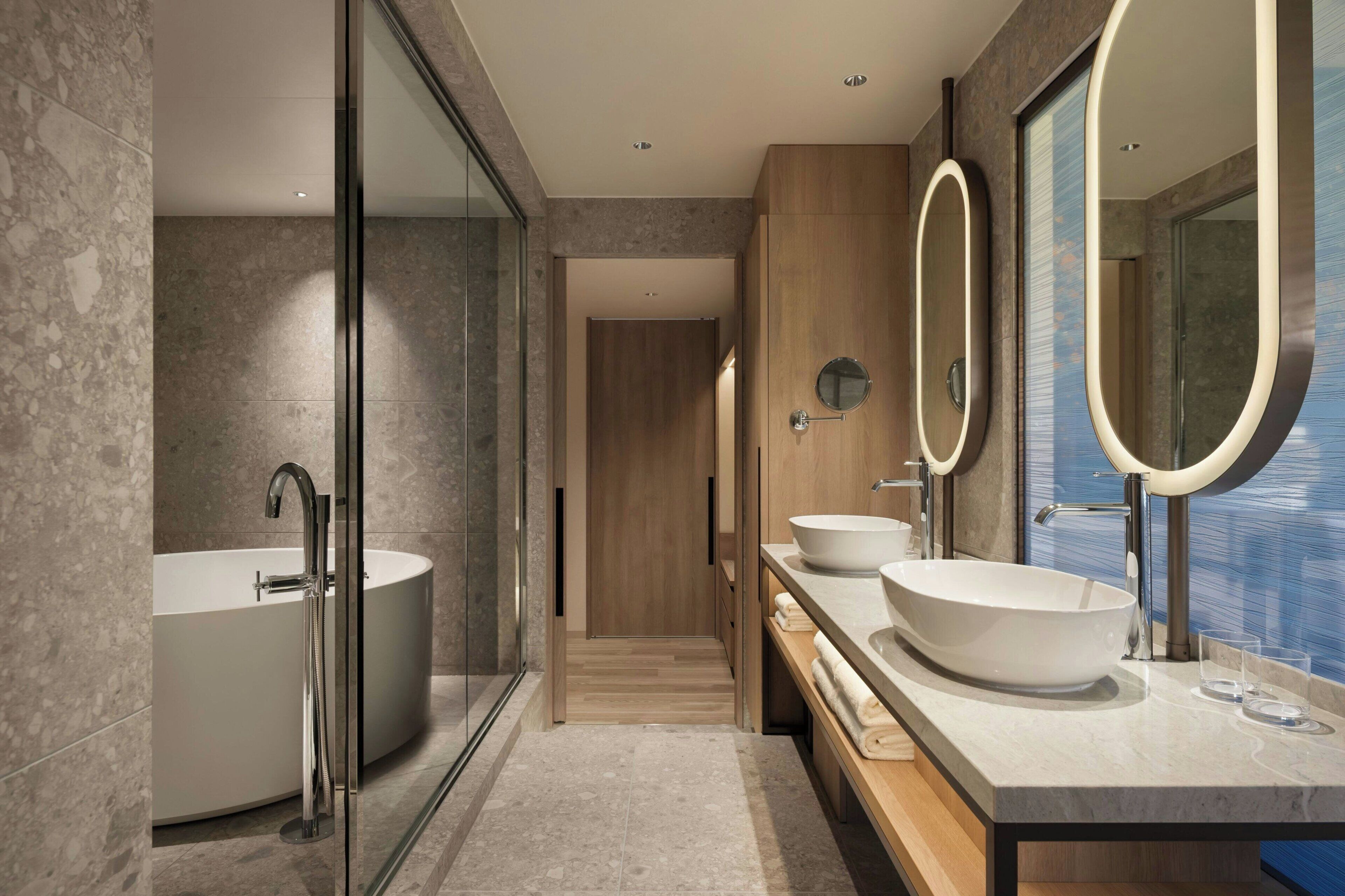 A modern bathroom with a freestanding bathtub, two vessel sinks, and a large mirror.
