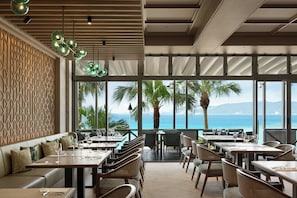A restaurant with a view of the sea, featuring tables and chairs arranged for dining. - Courtyard by Marriott Okinawa Resort (Nago)