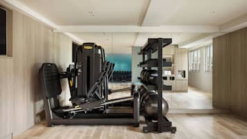 A modern gym with exercise equipment, a mirrored wall, and a view of the outside.