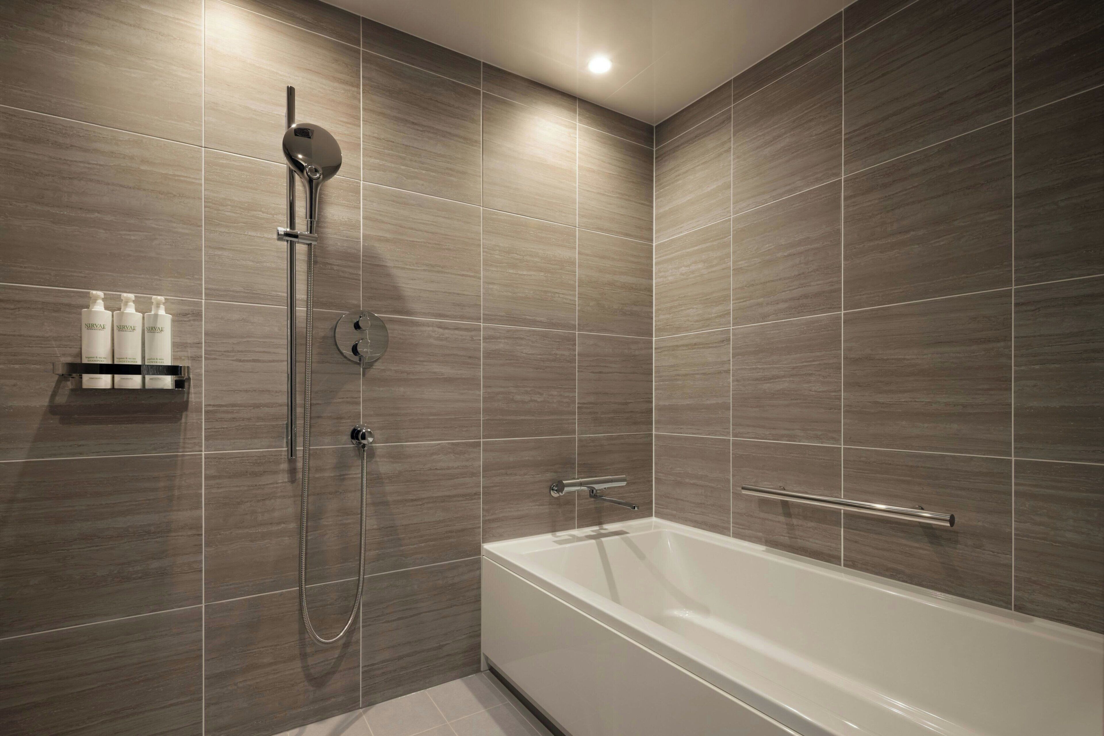 A modern bathroom with a shower, a bathtub, and a shelf with toiletries.