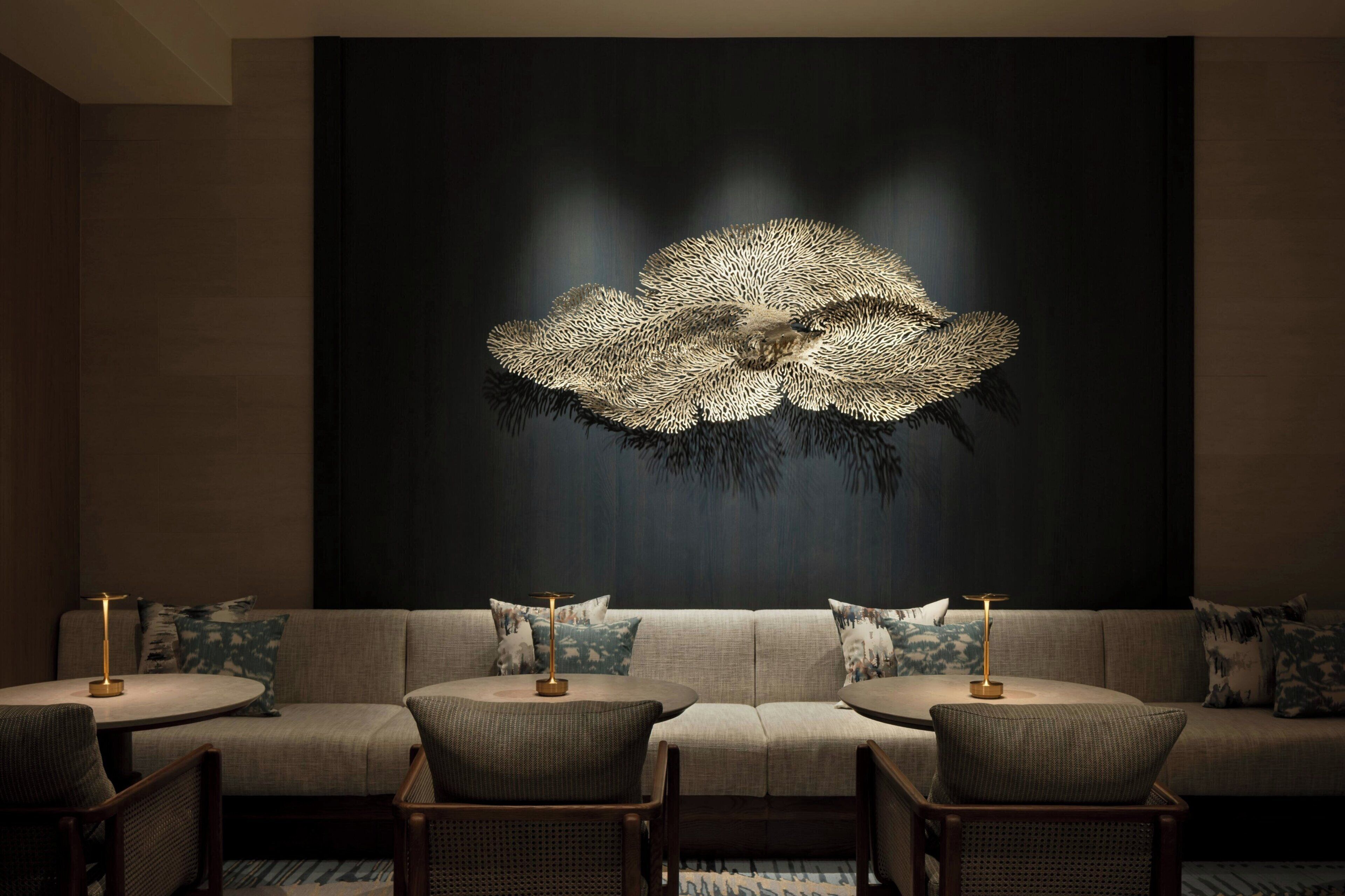 A modern living room with a sofa set, round tables, and a large abstract wall art piece.