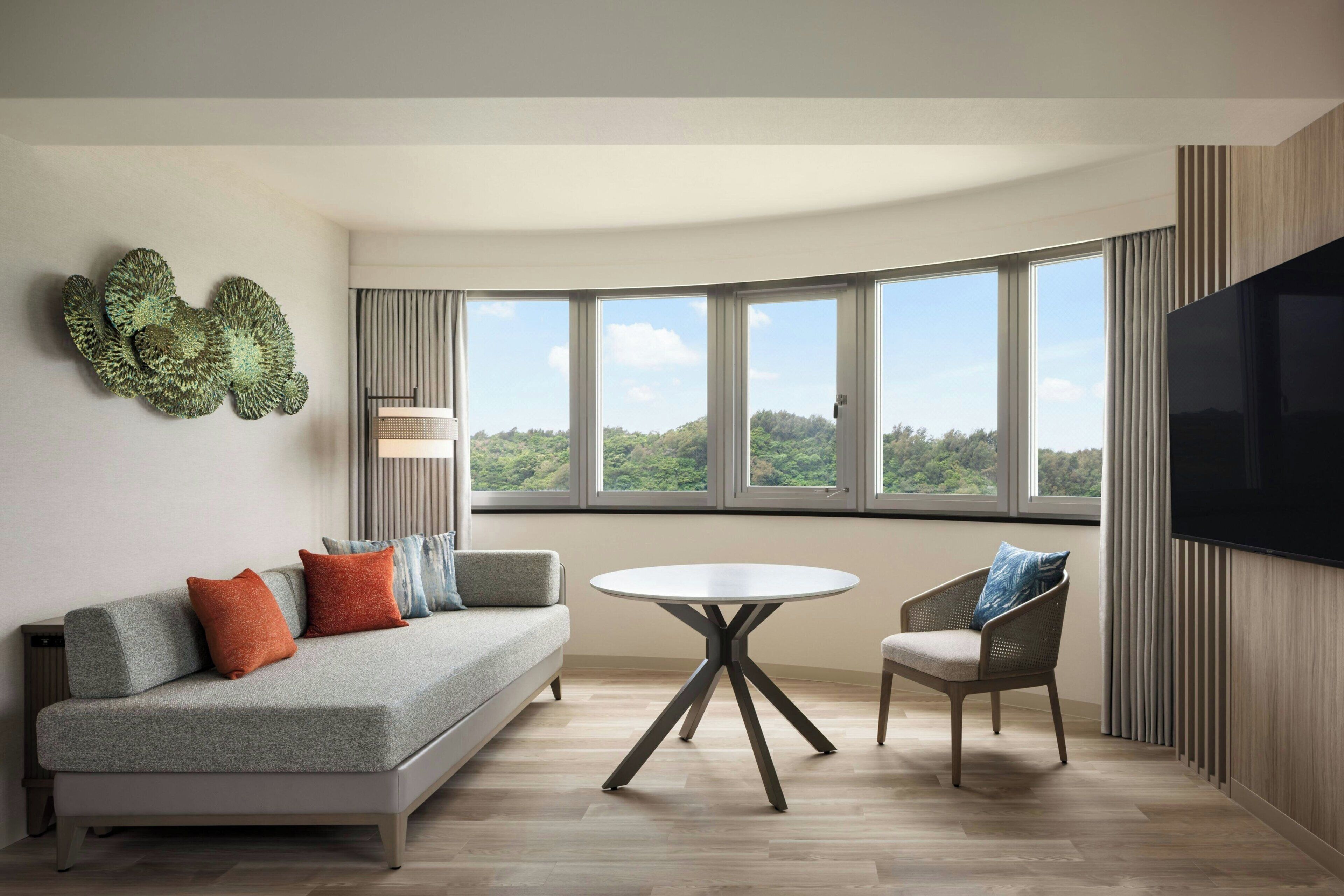 A modern living room with a sofa, a round table, and a TV.