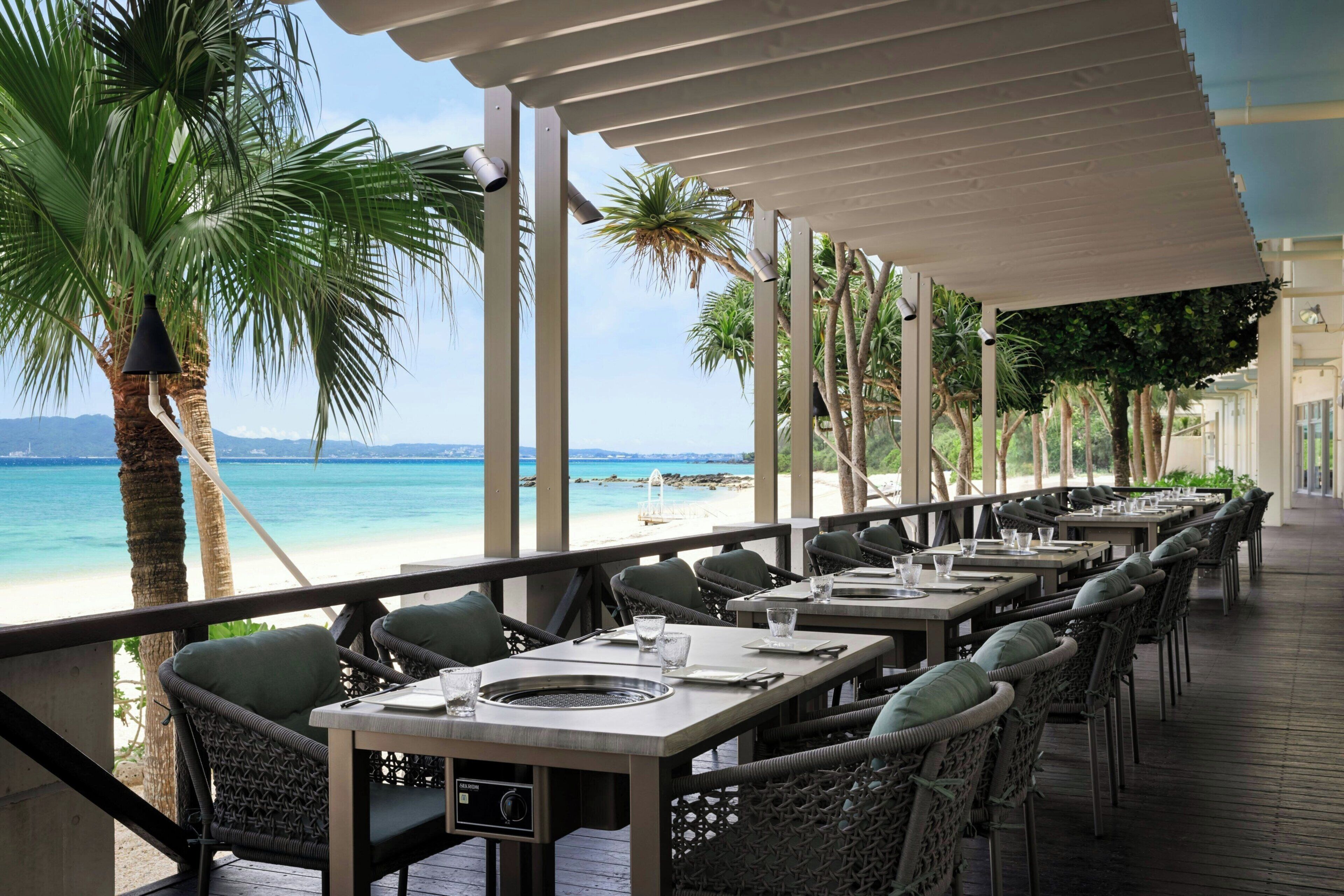A seaside restaurant with outdoor seating, overlooking the beach and ocean.