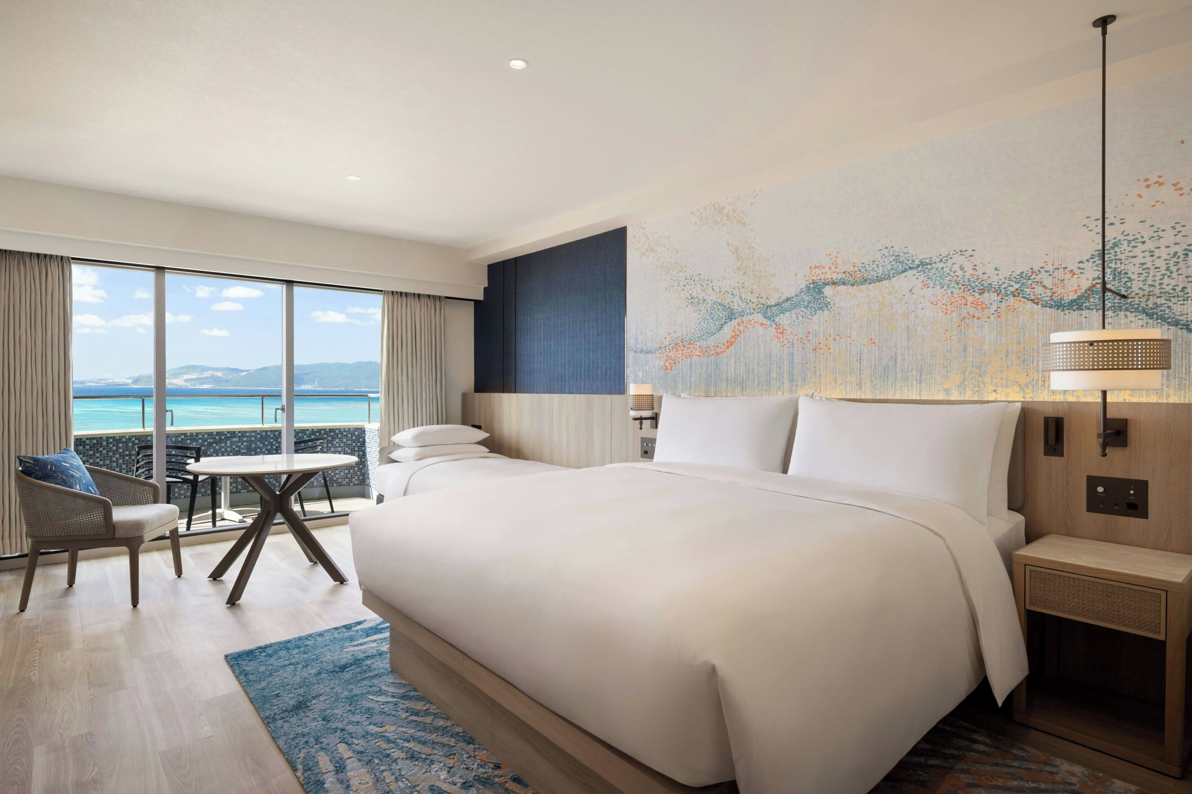 Une chambre d’hôtel avec un grand lit, un bureau et une vue sur la mer.