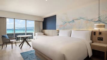 Habitación de hotel con una cama grande, un escritorio y vista al mar.