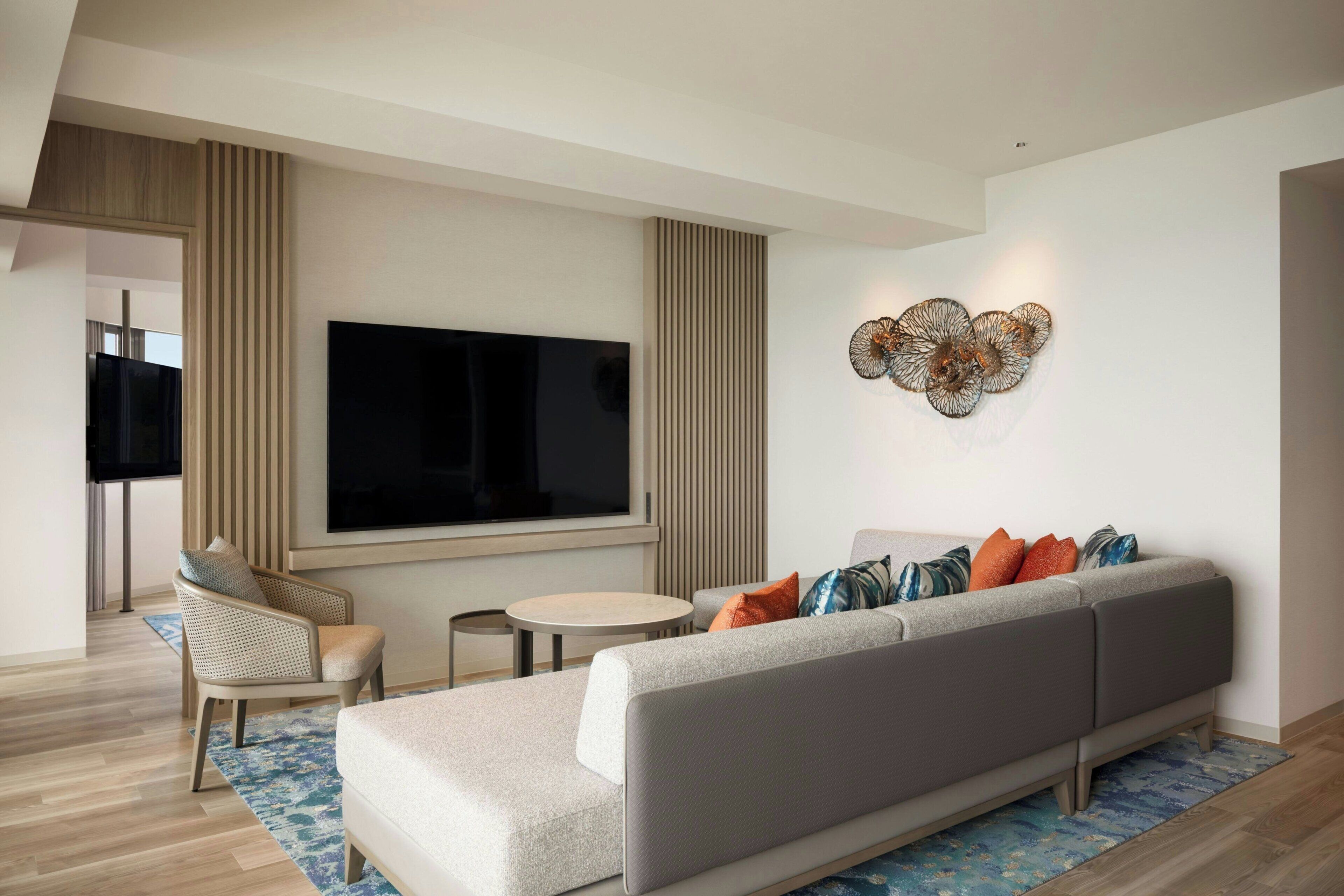 A modern living room with a sofa, a TV, and a decorative wall piece.