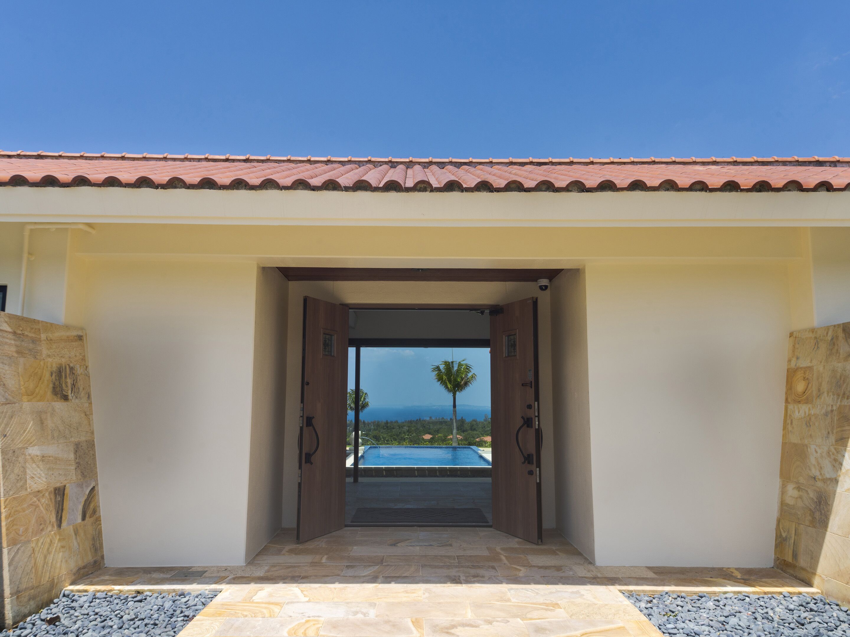 An entrance to a building with a view of a swimming pool and mountains.