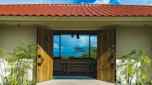 A wooden door leading to a room with a bench and a view of the ocean. - Kanehide Kise Country Club (Nago)