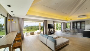 A spacious living area with a sofa, a dining table, and a kitchen area. - Kanehide Kise Country Club (Nago)