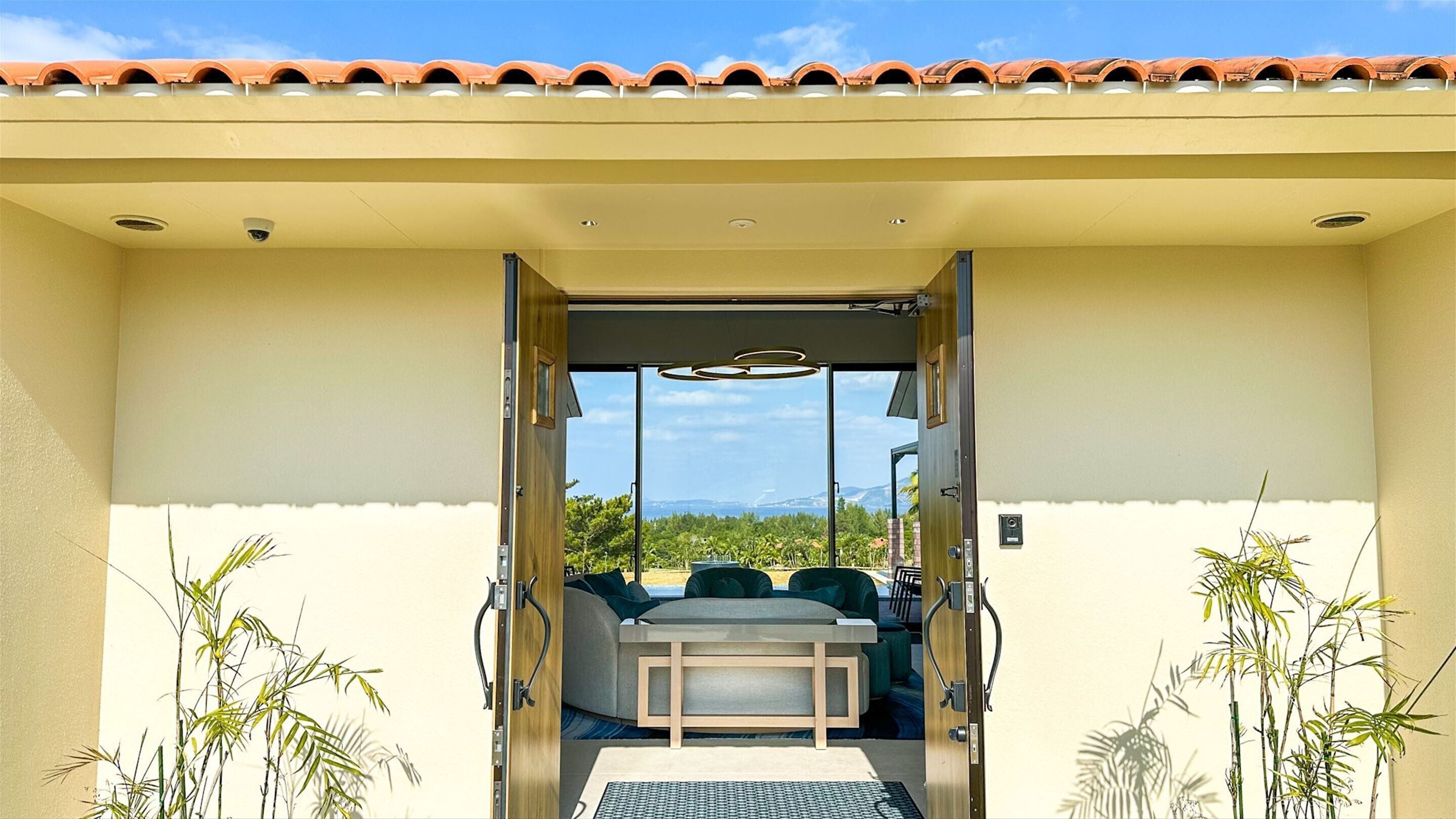 An open doorway leading to a dining area with a table and chairs, surrounded by plants.