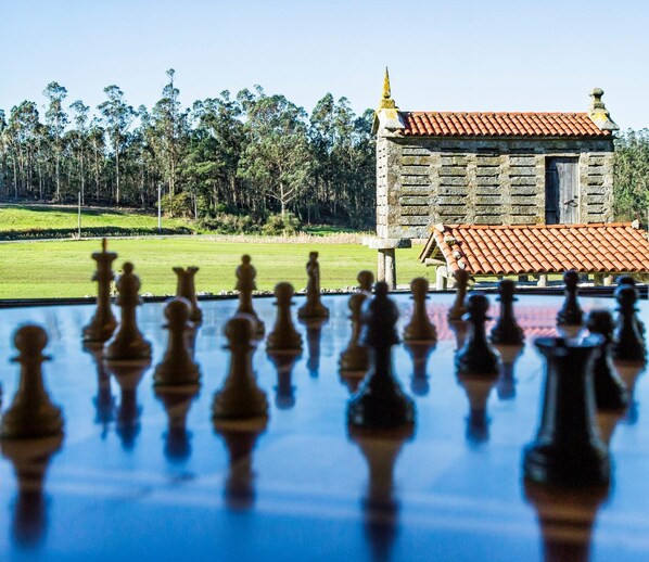 A chessboard with pieces in front of a building with a tiled roof. - Casa Castiñeira (Muxía)