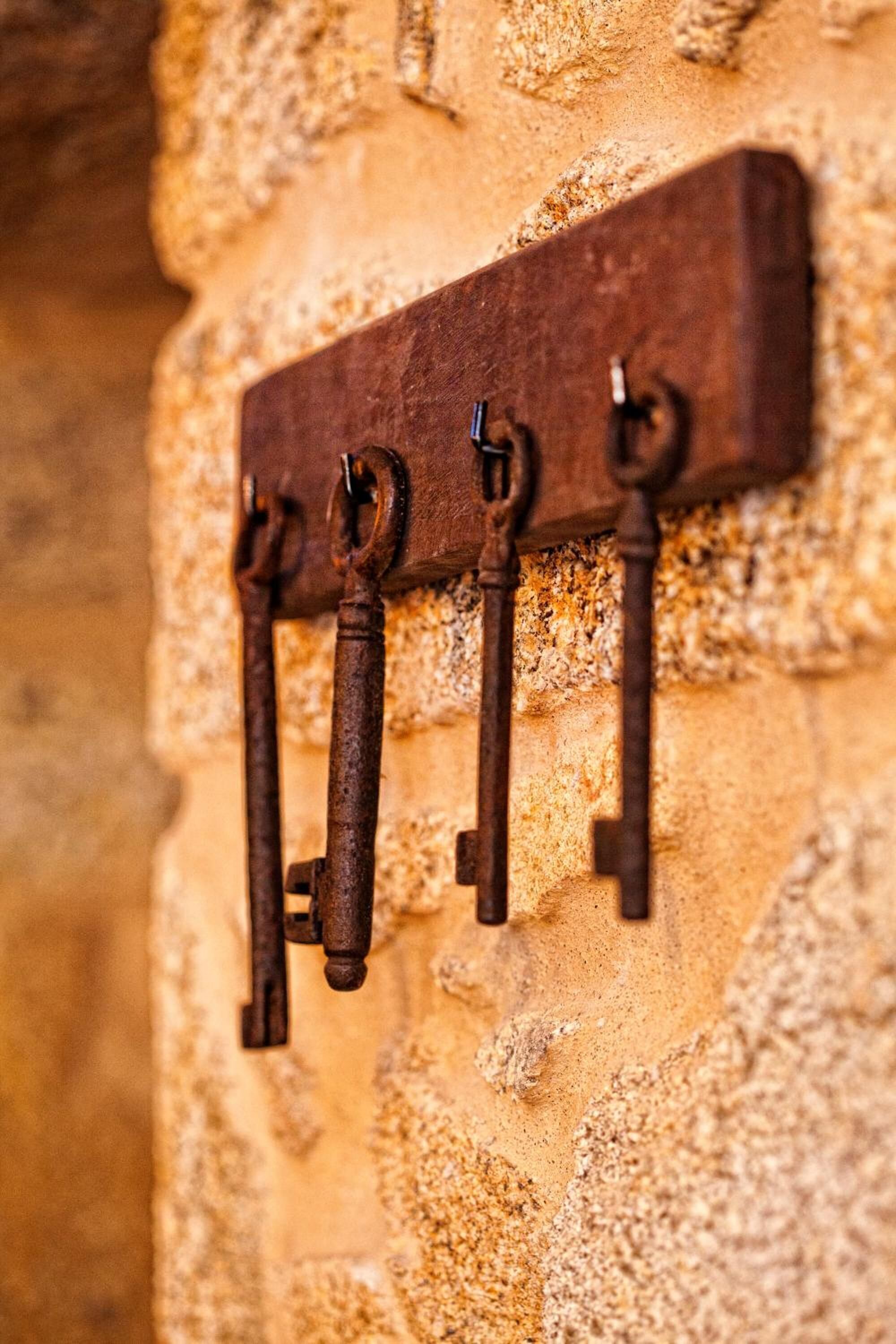 Un gancho metálico fijado a la pared con una placa de madera rectangular.