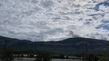 En flod med et bjerglandskab i baggrunden og en overskyet himmel.