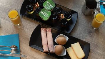 A breakfast table with croissants, bananas, apples, eggs, cheese, and condiments.
