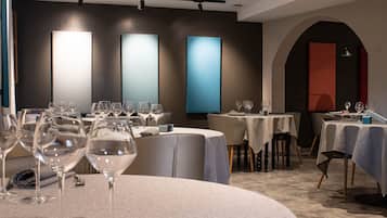 A restaurant with round tables, each set with wine glasses and napkins.