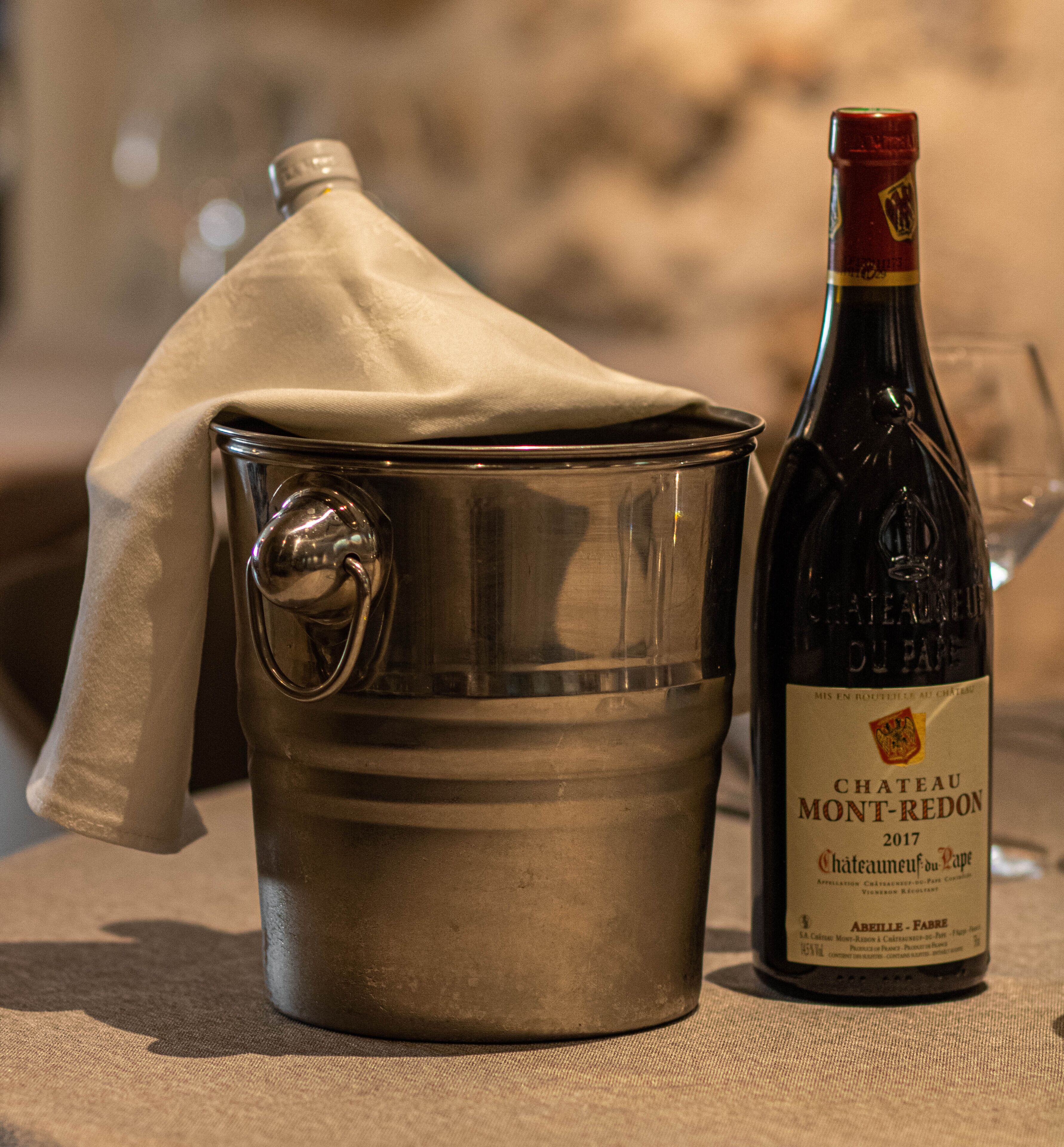 A metal bucket with a cloth cover and a bottle of Chateau Mont-Redon wine from 2017.