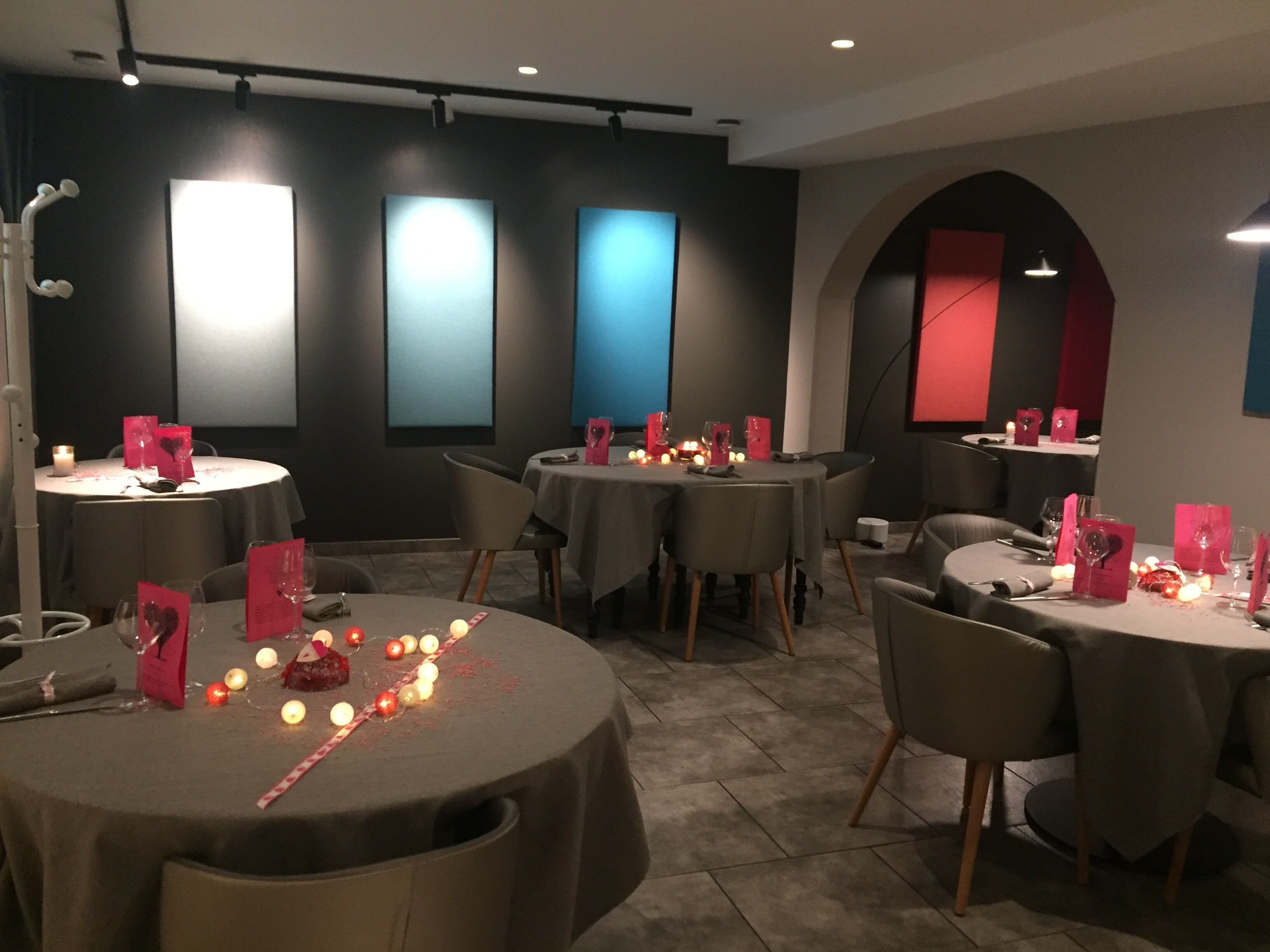Restaurante com mesas redondas, velas e suportes de menu vermelhos.