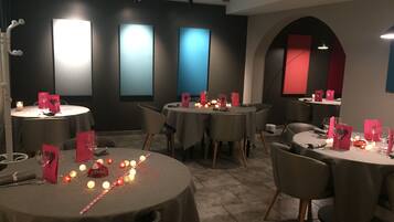Restaurante com mesas redondas, velas e suportes de menu vermelhos.
