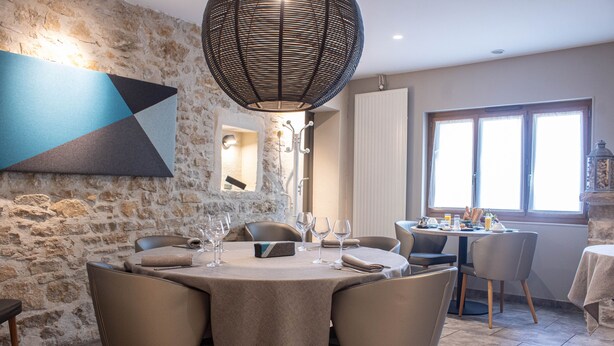 Comedor con pared de piedra, un cuadro abstracto de gran tamaño y una lámpara moderna.