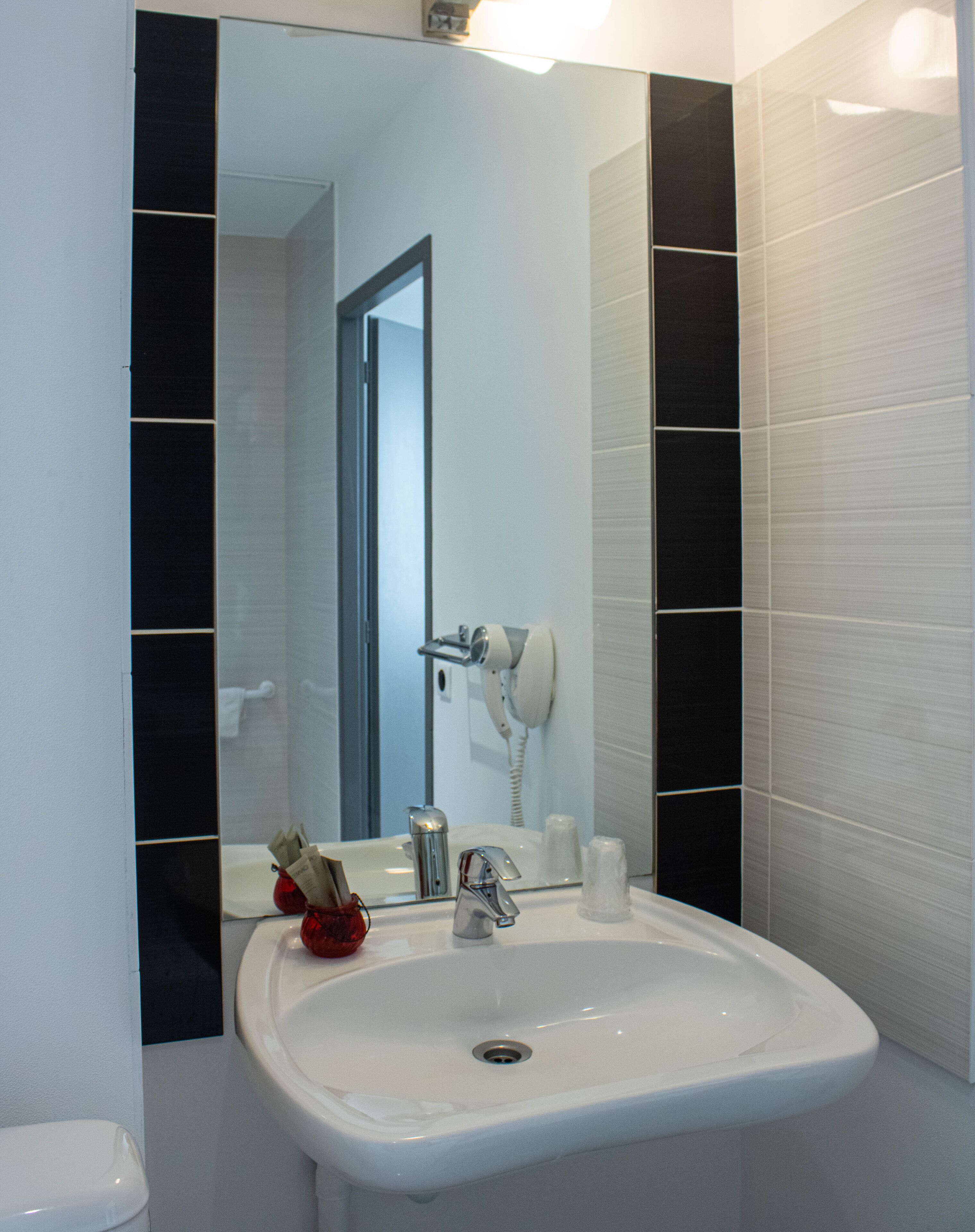 A bathroom with a white sink, a hairdryer, and a toilet.