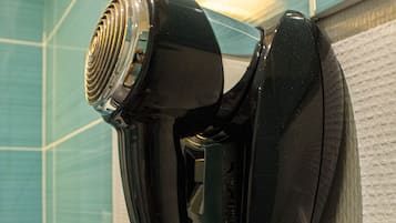 A wall-mounted hair dryer in a bathroom with blue tiles.
