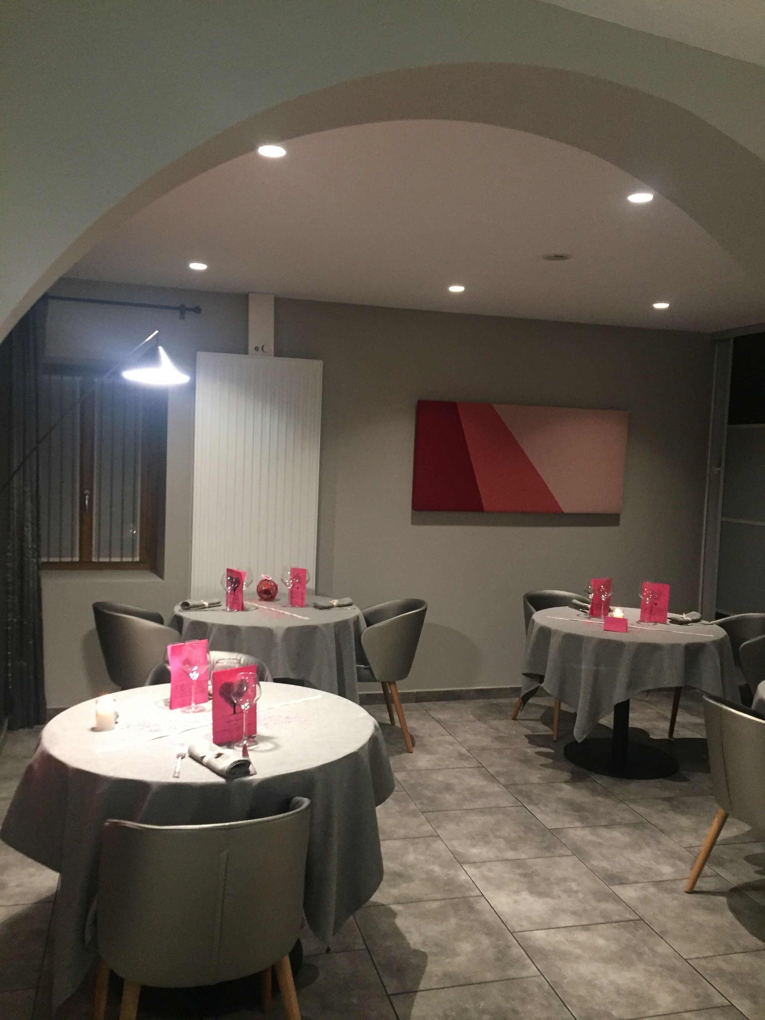 Un espace repas avec des tables rondes, des chaises grises et un design moderne au plafond.