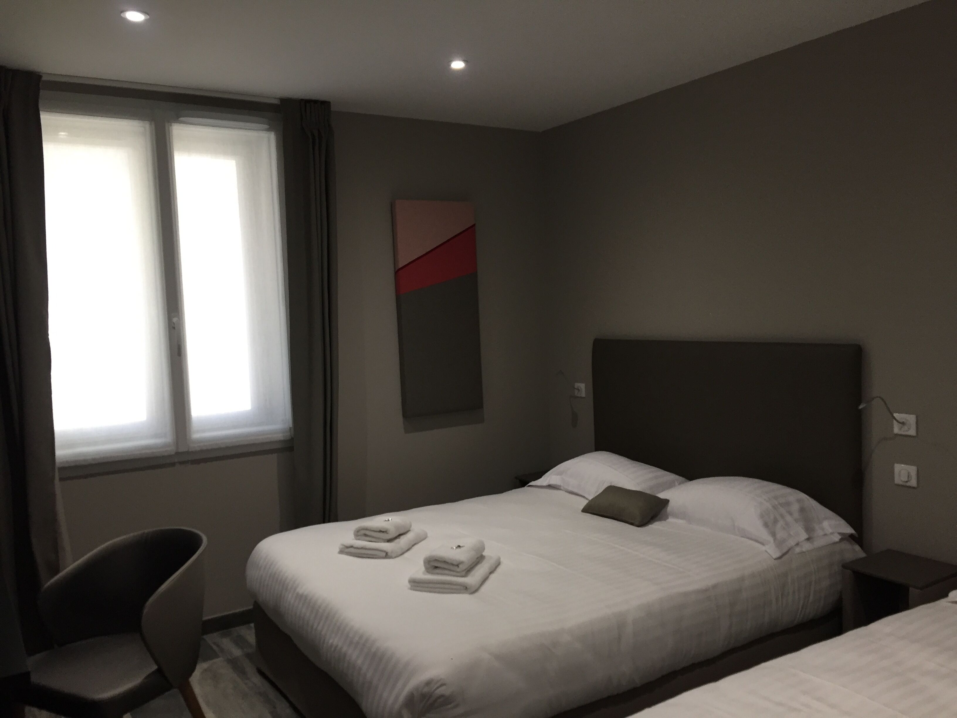 Une chambre d’hôtel avec un lit, une chaise et une fenêtre avec des rideaux.