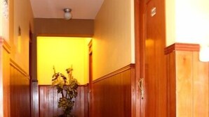 A hallway with wooden paneling, a potted plant, and a door with a sign. - Hotel El Tumi 2 (Huaraz)