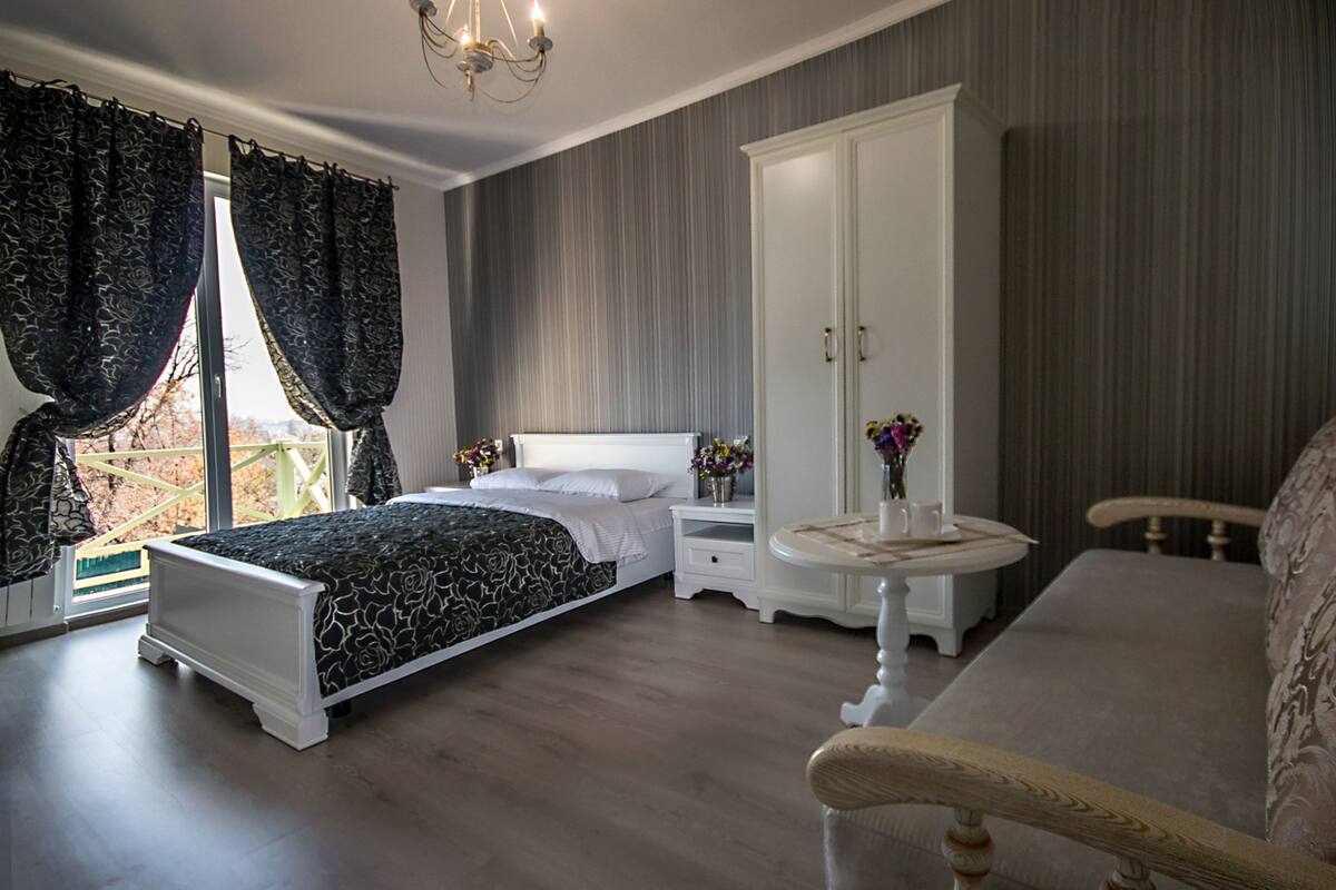 A bedroom with a bed, nightstands, a wardrobe, and a sofa.