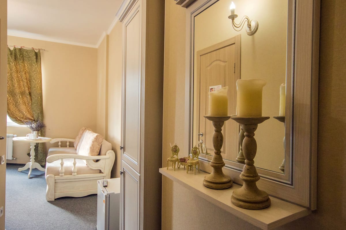 A room with a white sofa, a small table with a vase, and a mirror with candles.