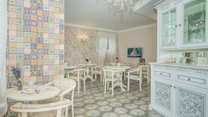 A dining area with a tiled wall, white furniture, and a cabinet with glass doors. - Ryleev Hotel (Kharkiv)