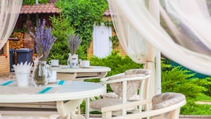 An outdoor dining area with white furniture, a pitcher, and a cup on a table. - Ryleev Hotel (Kharkiv)