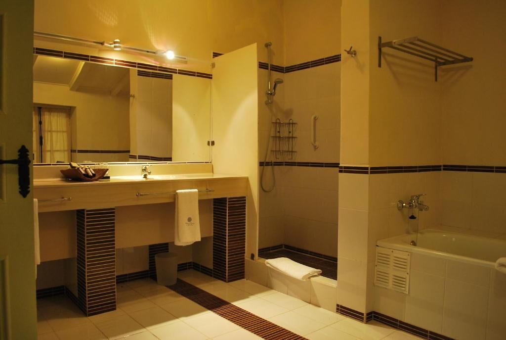 A bathroom with a bathtub, a shower, a sink with a mirror, and a towel rack.