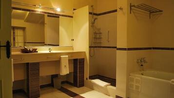 A bathroom with a bathtub, a shower, a sink with a mirror, and a towel rack.