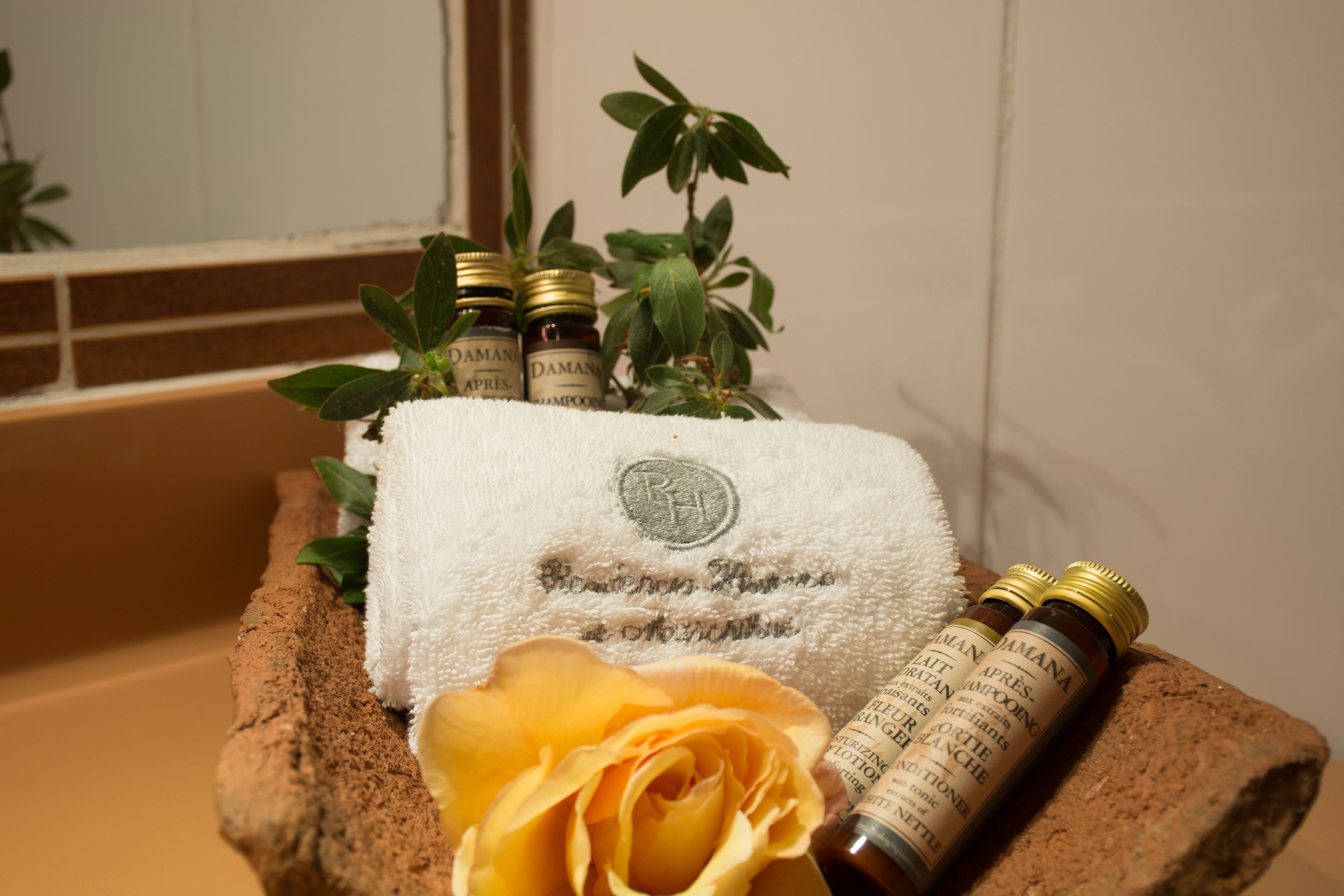 A bathroom with a bathtub, a towel, a rose, and two bottles of shampoo.