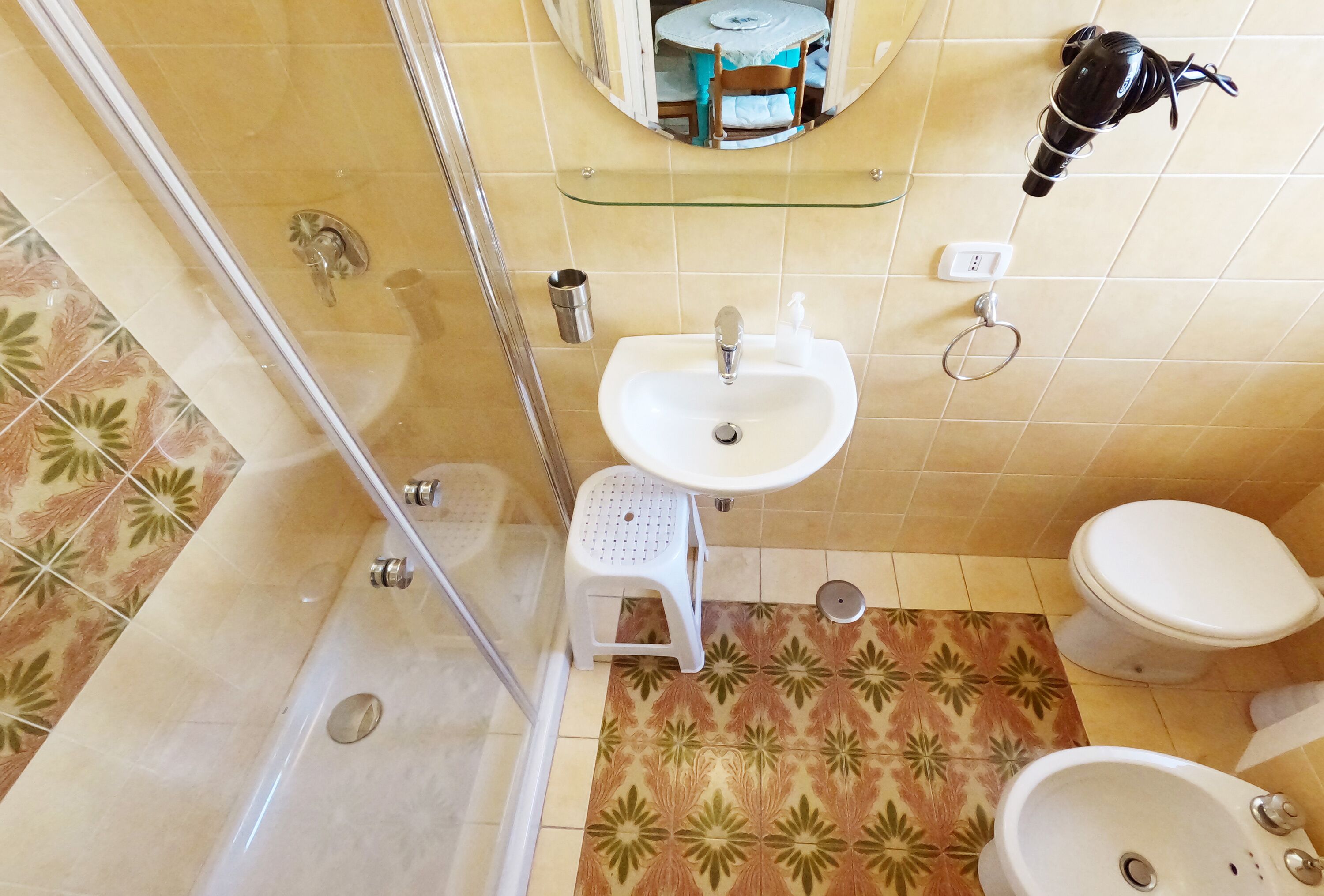 A bathroom with a shower, a sink, a toilet, and a mirror.