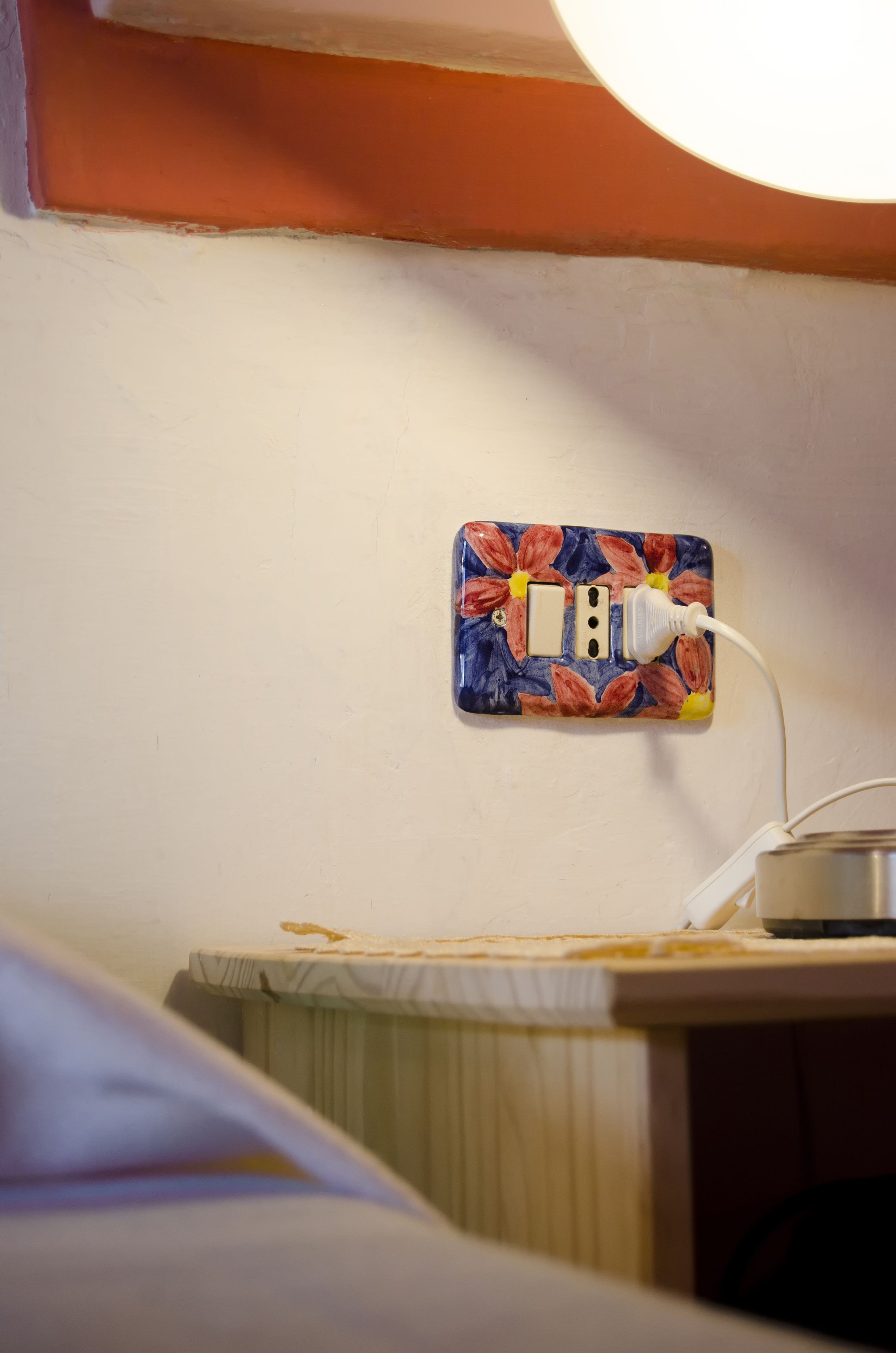 A power outlet with a floral cover plate on a white wall.