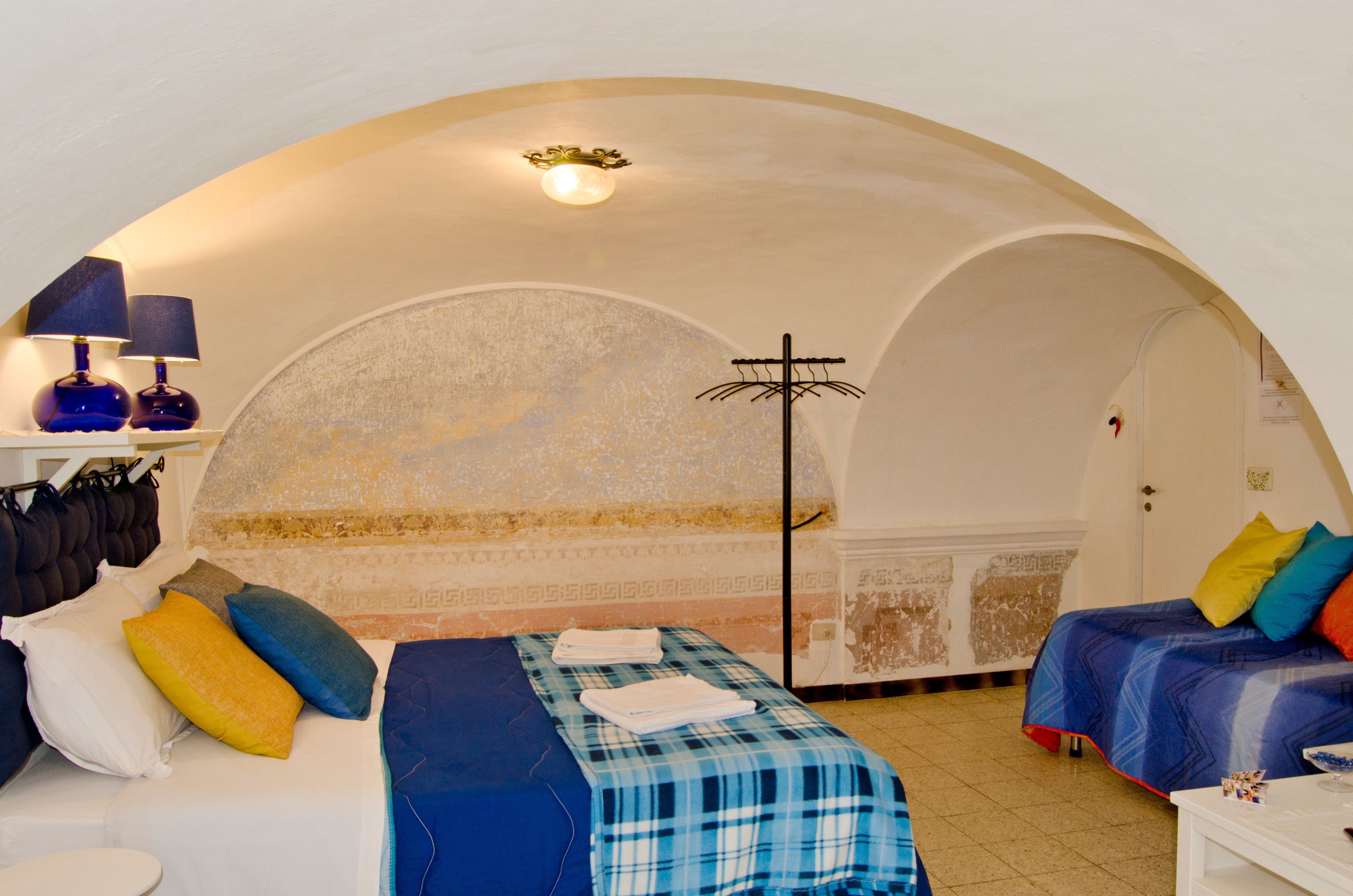 Una habitación con cama, mesita de noche, lámpara y armario.