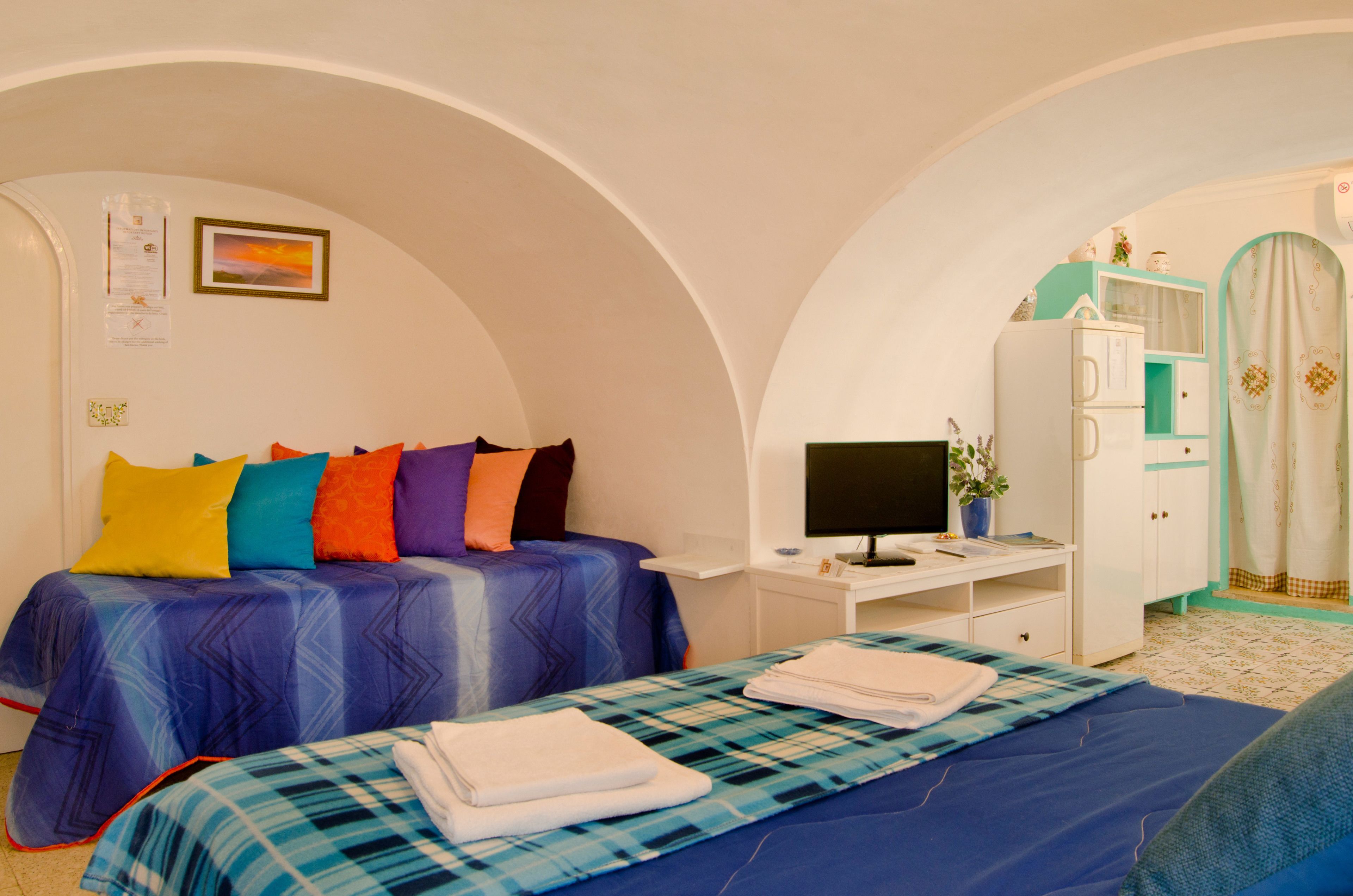 A bedroom with two beds, a desk, a TV, and a wardrobe.