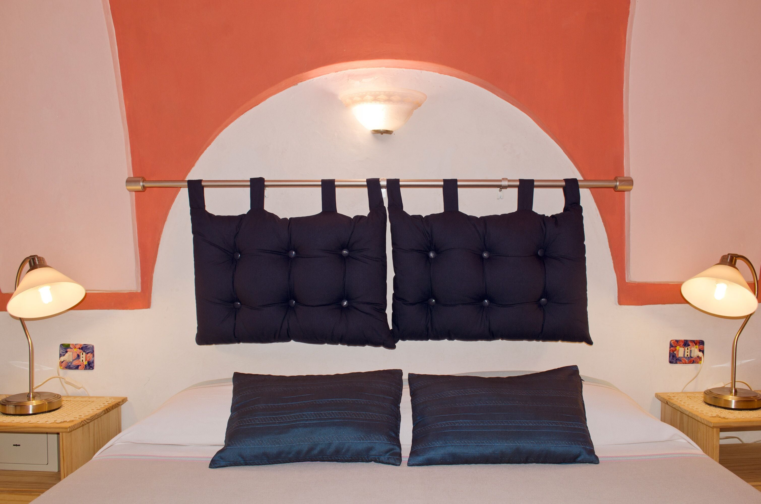 Een hotelkamer met een bed, twee nachtkastjes, een hoofdeinde en een boog in de muur.