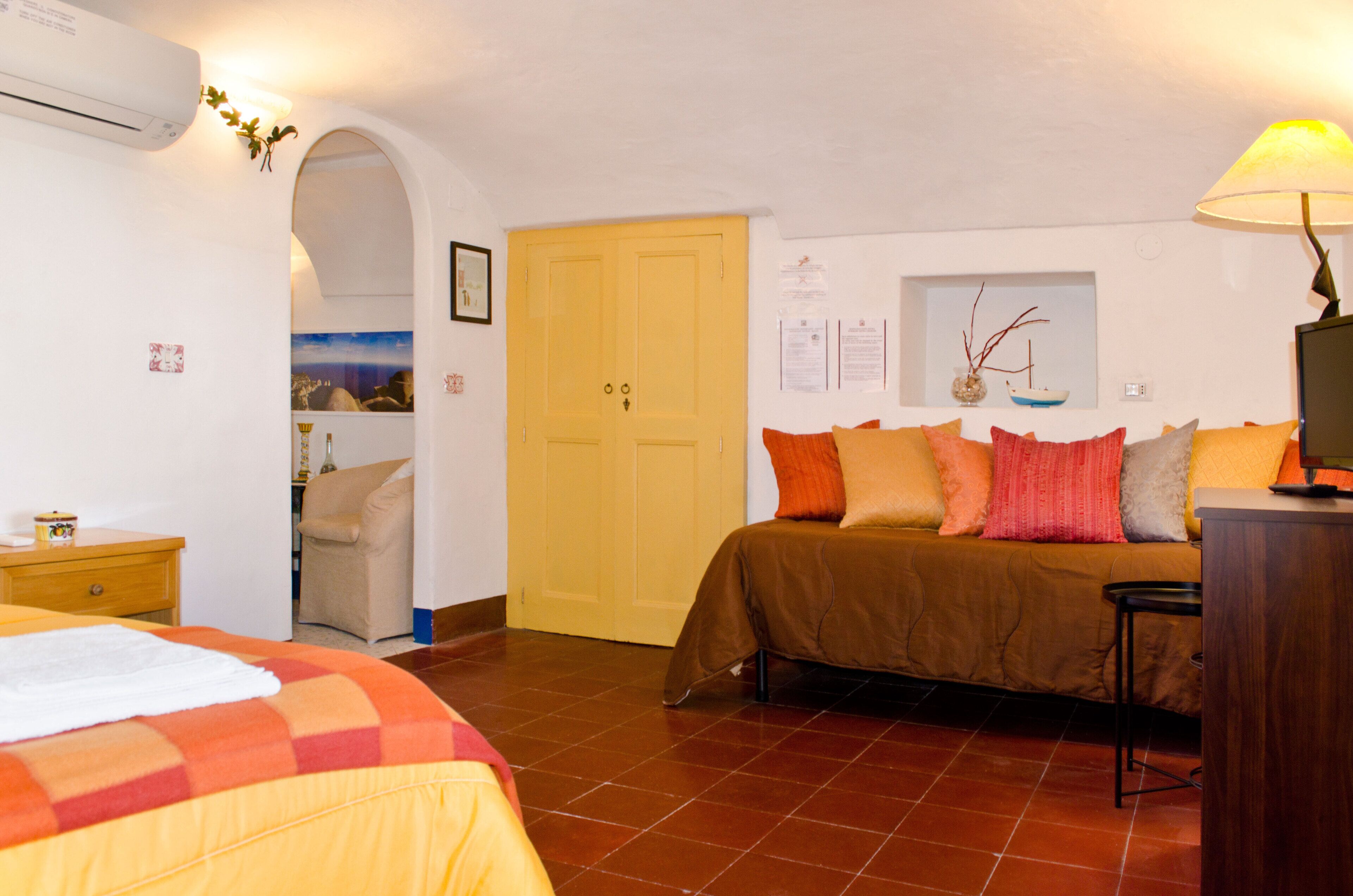Een slaapkamer met een bed, een stoel, een bureau en een airconditioning.