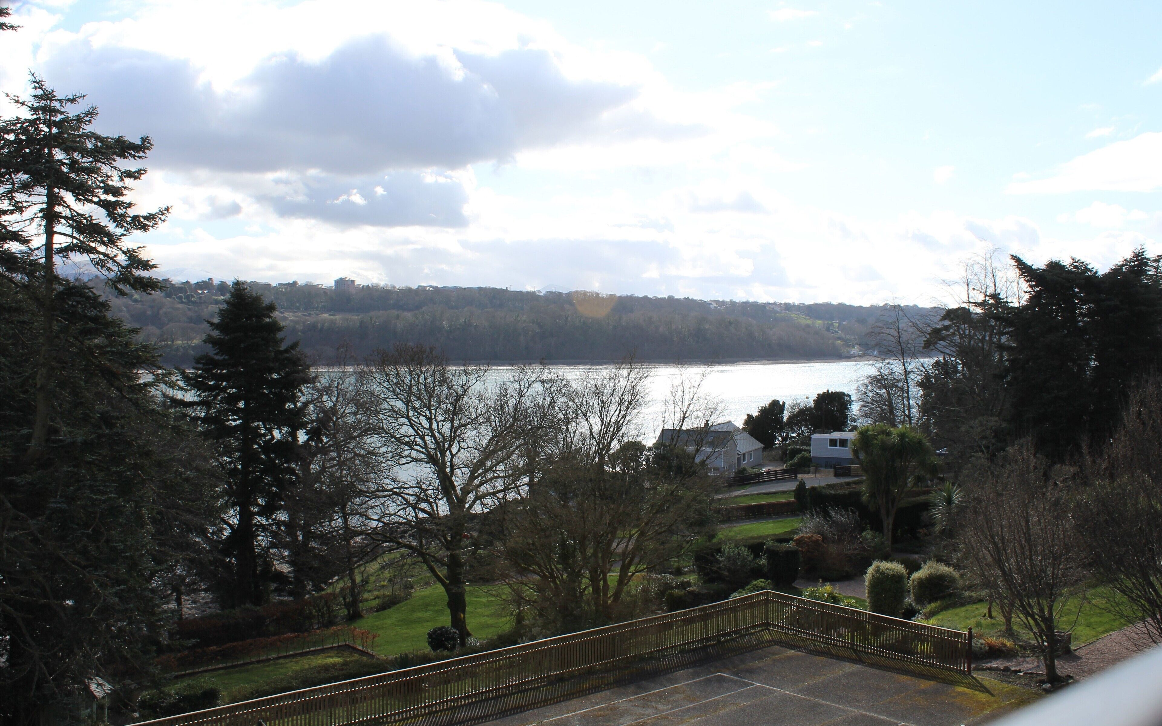 A view of a lake with a house and trees in the foreground.