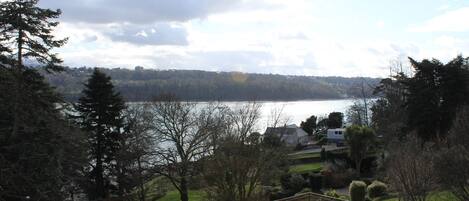 A view of a lake with a house and trees in the foreground.