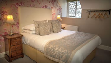 Un dormitorio con una cama, dos mesitas de noche, una ventana y un radiador.