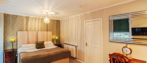 A bedroom with a large bed, bedside lamps, a wooden chair, a mirror, and a view of the outside.