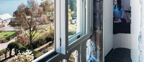 A room with a large arched window overlooking a lake and garden.