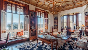 Amplia habitación con ventanas grandes, una araña y una colección de estanterías.