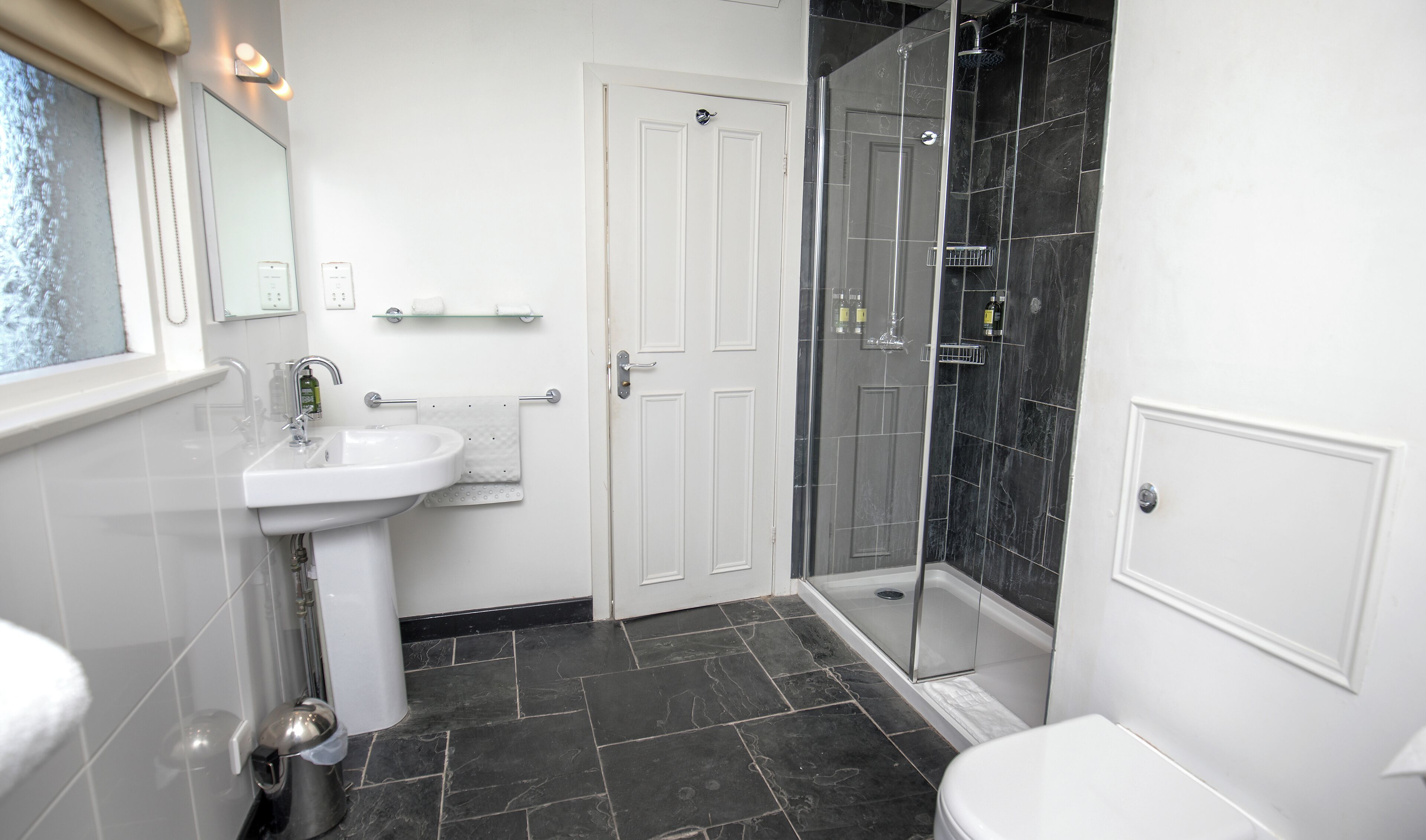A bathroom with a white sink, a glass shower enclosure, and a white toilet.