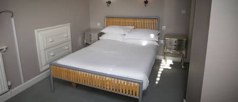 A neatly made bed with a wooden headboard, two bedside tables with lamps, and a white dresser with drawers.